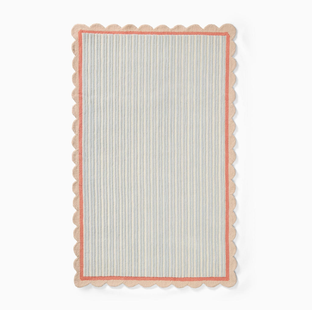 Hand-tufted wool area rug by COZY CARPETS featuring pastel blue and ivory vertical stripes, a coral pink inner border, and a scalloped beige edge on a white background.