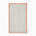 Hand-tufted wool area rug by COZY CARPETS featuring pastel blue and ivory vertical stripes, a coral pink inner border, and a scalloped beige edge on a white background.