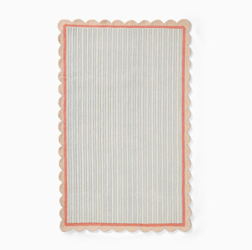 Hand-tufted wool area rug by COZY CARPETS featuring pastel blue and ivory vertical stripes, a coral pink inner border, and a scalloped beige edge on a white background.